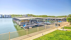 Un port de plaisance avec des bateaux amarrés, une zone abritée pour la mise à l’eau des bateaux, et une vue sur un paysage urbain en arrière-plan.