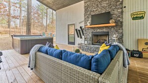 Ein gemütlicher Außenbereich mit Kamin aus Stein, einer bequemen Couch und einem Whirlpool.