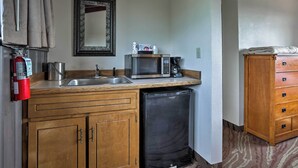 A compact kitchen with a sink, microwave, and a small refrigerator. There is a wooden cabinet and a fire extinguisher mounted on the wall. - Burkesville Apt w/ Deck, Views & Pool Access! (Burkesville)