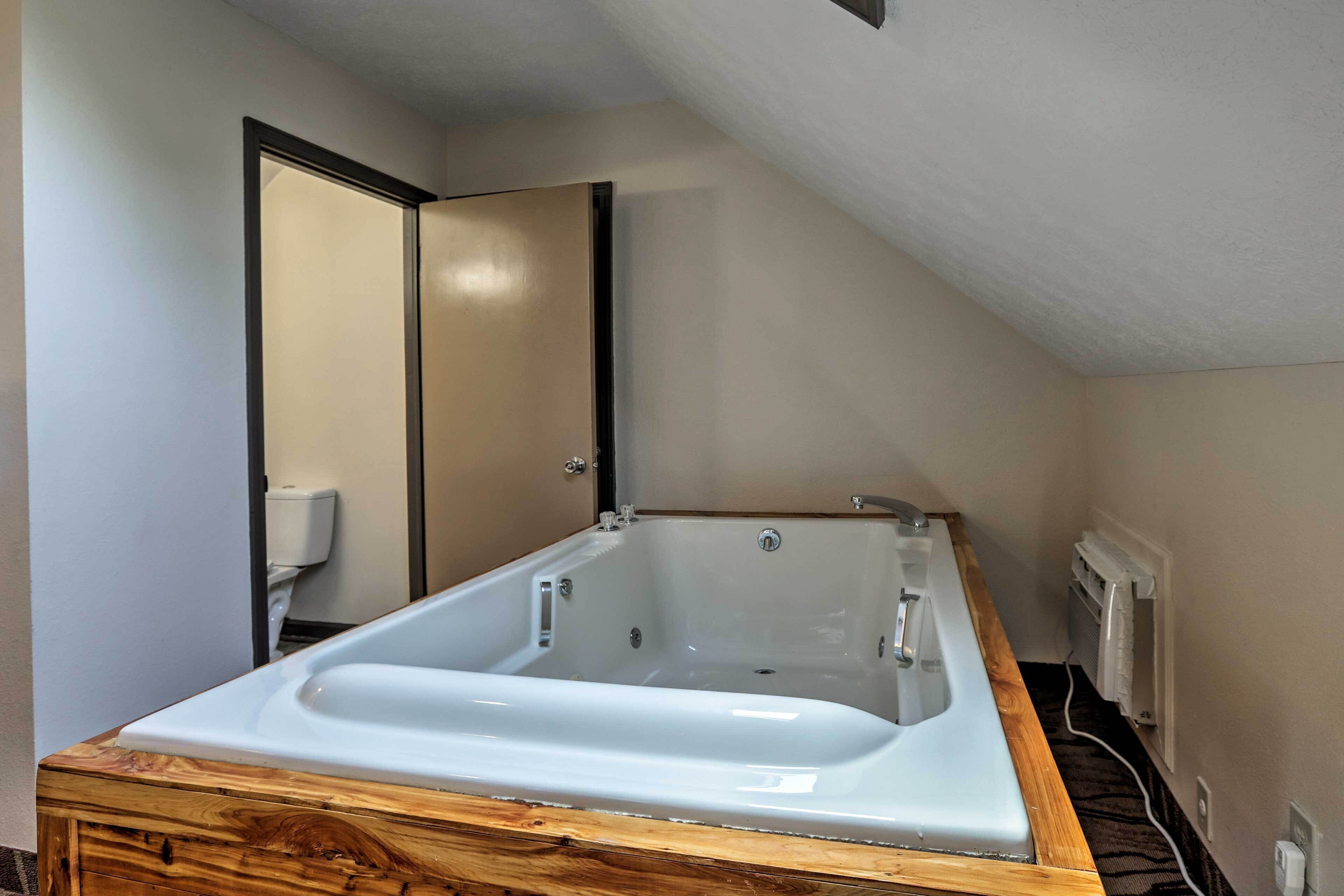 Een moderne badkamer met een vrijstaand bad, een houten wastafelmeubel en een spiegelwand.