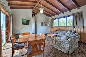 A spacious room with a wooden dining table, chairs, a patterned sofa, and a television mounted on the wall. - Burkesville Apt w/ Deck, Views & Pool Access! (Burkesville)
