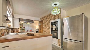 Une cuisine moderne avec un mur d’accent en briques, des appareils en acier inoxydable et un plan de travail en bois.