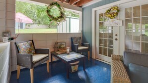 Une pièce chaleureuse, meublée de meubles en osier, avec une table agrémentée d’un objet décoratif et une porte sur laquelle est apposée une pancarte indiquant « Sunshine ».