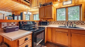 A kitchen with wooden cabinets, a stove, a microwave, and a sink.