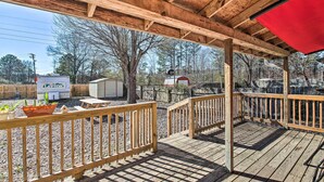 A wooden deck with a covered area, a small shed, and a red barn in the background. - Central Hot Springs Family Home w/ Deck! (Hot Springs)