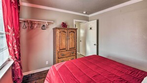 A bedroom with a red bedspread, wooden wardrobe, and a red curtain. - Central Hot Springs Family Home w/ Deck! (Hot Springs)
