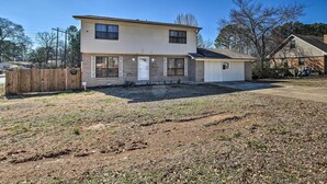 A two-story house with a front porch, a fenced yard, and a clear sky. - Central Hot Springs Family Home w/ Deck! (Hot Springs)