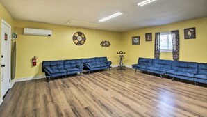 A spacious room with a wooden floor, two blue sofas, a fire extinguisher, and a ceiling fan. - Central Hot Springs Family Home w/ Deck! (Hot Springs)