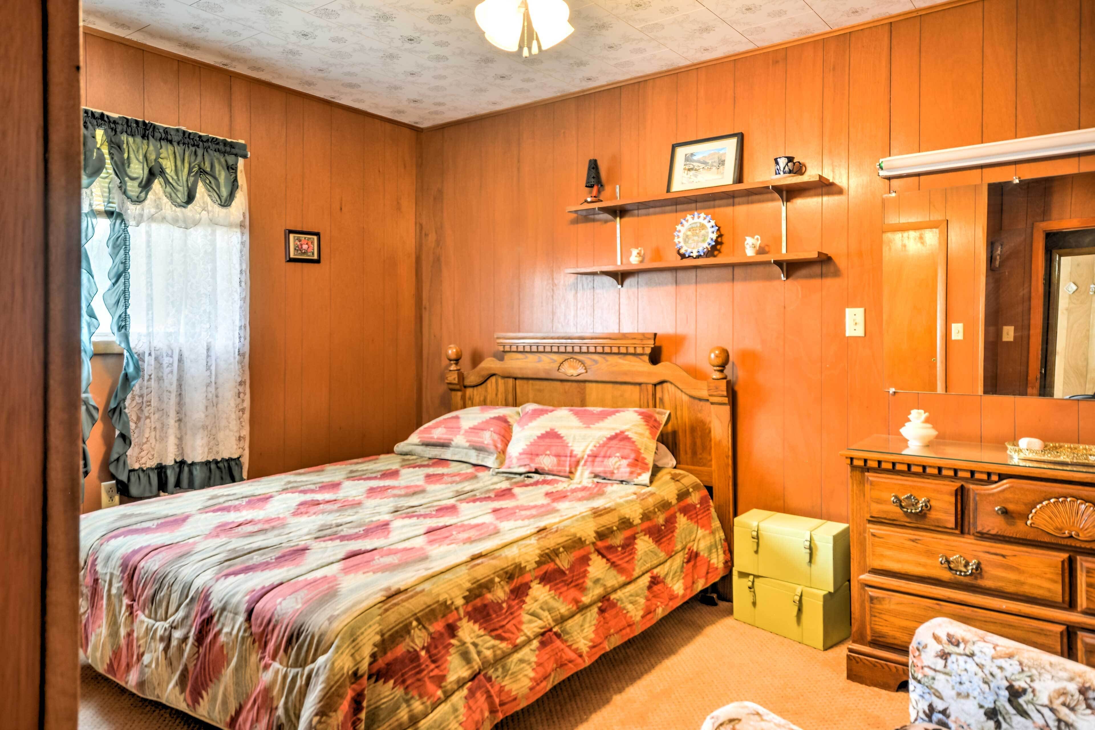 Un dormitorio con una cama de madera, un aparador, un espejo y una estantería con objetos decorativos.