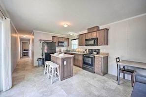 A modern kitchen with a central island, built-in appliances, and a dining area with a bench. - Cassopolis Cabin w/ Lake & Fishing Access! (Cassopolis)