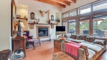 A cozy living room with a fireplace, comfortable seating, and a large window offering a view of the outdoors.