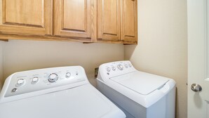 Un cuarto de lavandería con dos lavadoras de carga frontal y armarios de madera arriba.