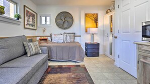 A bedroom with a bed, bedside table, lamp, and a large wall clock. - Central Elmont Studio w/ Great Outdoor Space! (Elmont)