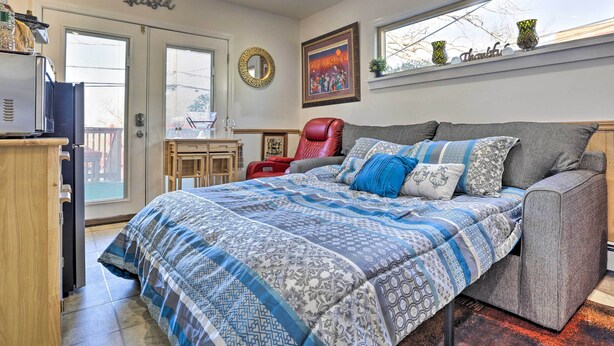 A bedroom with a bed, a red chair, a desk, and a window with a view. - Central Elmont Studio w/ Great Outdoor Space! (Elmont)