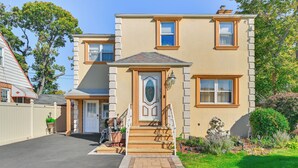 A two-story house with a front porch, a small garden, and a driveway. - Central Elmont Studio w/ Great Outdoor Space! (Elmont)