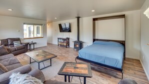 A spacious living room with a large bed, a sofa, a coffee table, and a television mounted on the wall. - Charming Cle Elum Home w/ Patio: 5 Mi to Dtwn! (Cle Elum)