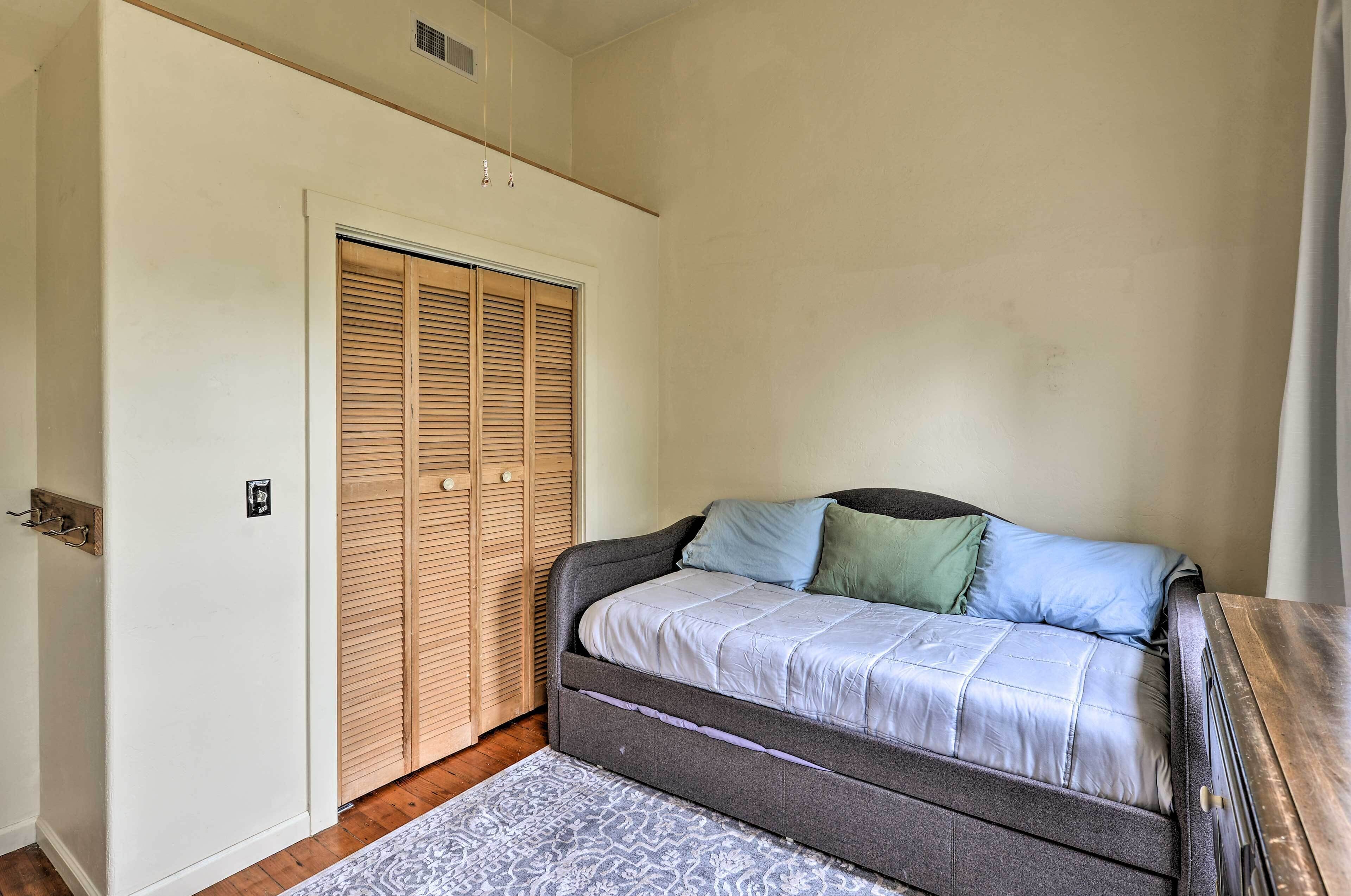 A bedroom with a bed, a wooden closet, and a patterned rug.