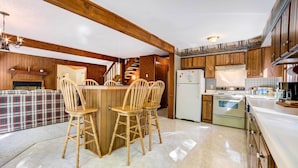 Eine Küche mit Holzausstattung, einer zentralen Kochinsel mit Sitzgelegenheiten, einem Kühlschrank und einem Herd.