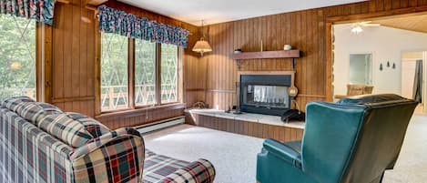 A cozy living room with a fireplace, plaid sofa, and a teal armchair.
