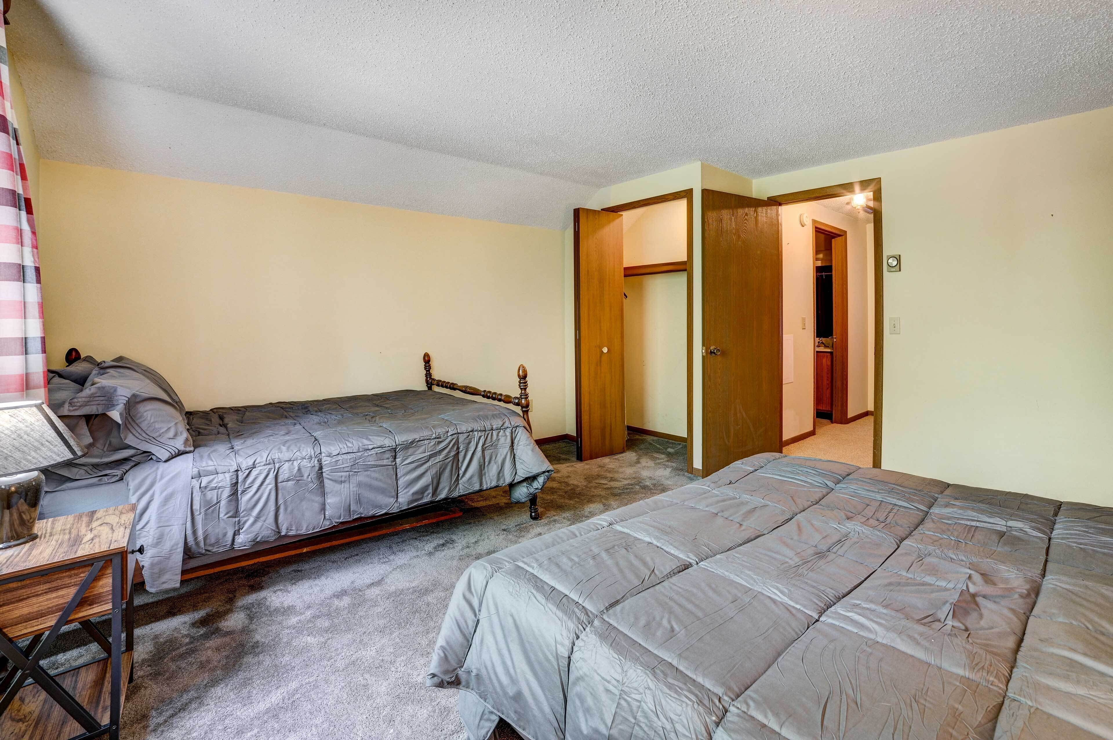 Un dormitorio con dos camas individuales, una mesita de noche de madera y un armario.