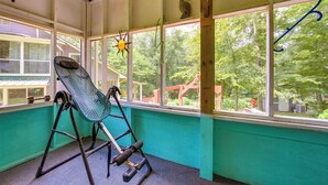 Une pièce avec un fauteuil à bascule, de grandes fenêtres et une vue sur les arbres.