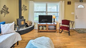 Un salon avec une cheminée, un téléviseur, un fauteuil rouge et un canapé.