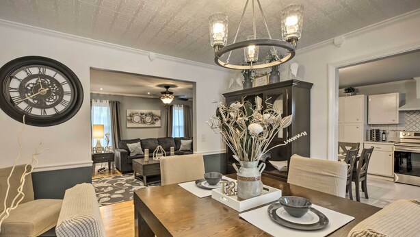A dining area with a wooden table, chairs, and a chandelier. There is a clock on the wall and a kitchen in the background. - Chattanooga House Rental w/ Private Backyard! (Chattanooga)
