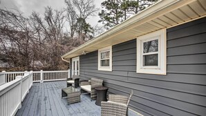 A covered deck with wicker furniture and a white railing. - Chattanooga House Rental w/ Private Backyard! (Chattanooga)