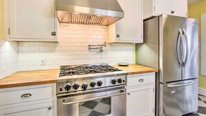 A kitchen with white cabinets, a stainless steel stove, and a refrigerator. - Charming Eugene Vacation Home: 1 Mi to Dtwn! (Eugene)