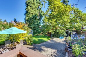 A patio with outdoor furniture, a gravel path, and a garden area with various plants and a small shed.