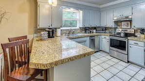 A kitchen with granite countertops, stainless steel appliances, and white cabinetry. - Sunroom & Yard: Charming Hot Springs Home! (Hot Springs)