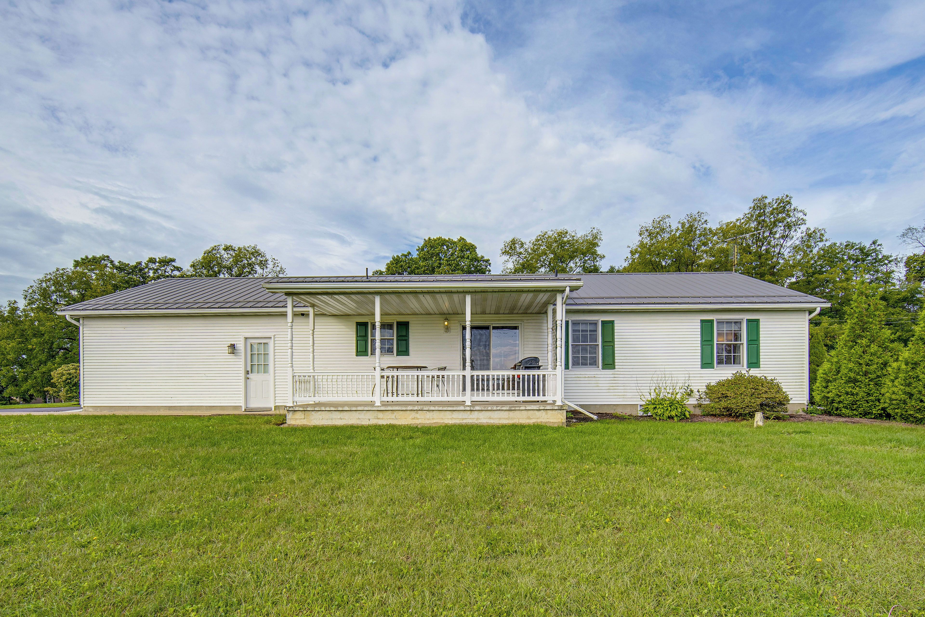 A two-story house with a front porch, a covered patio, and a well-maintained lawn.