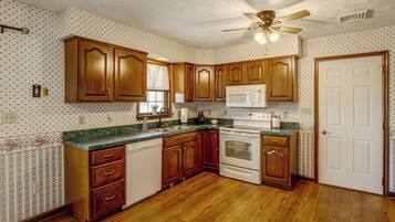 A kitchen with wooden cabinets, a microwave, a stove, and a ceiling fan.