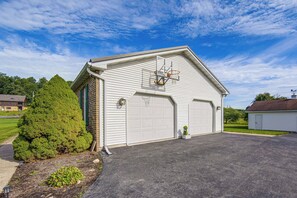 A single-story building with a garage door, a basketball hoop, and a small tree in front. - Charming Lewisburg Home w/ Hot Tub & Games! (Lewisburg)