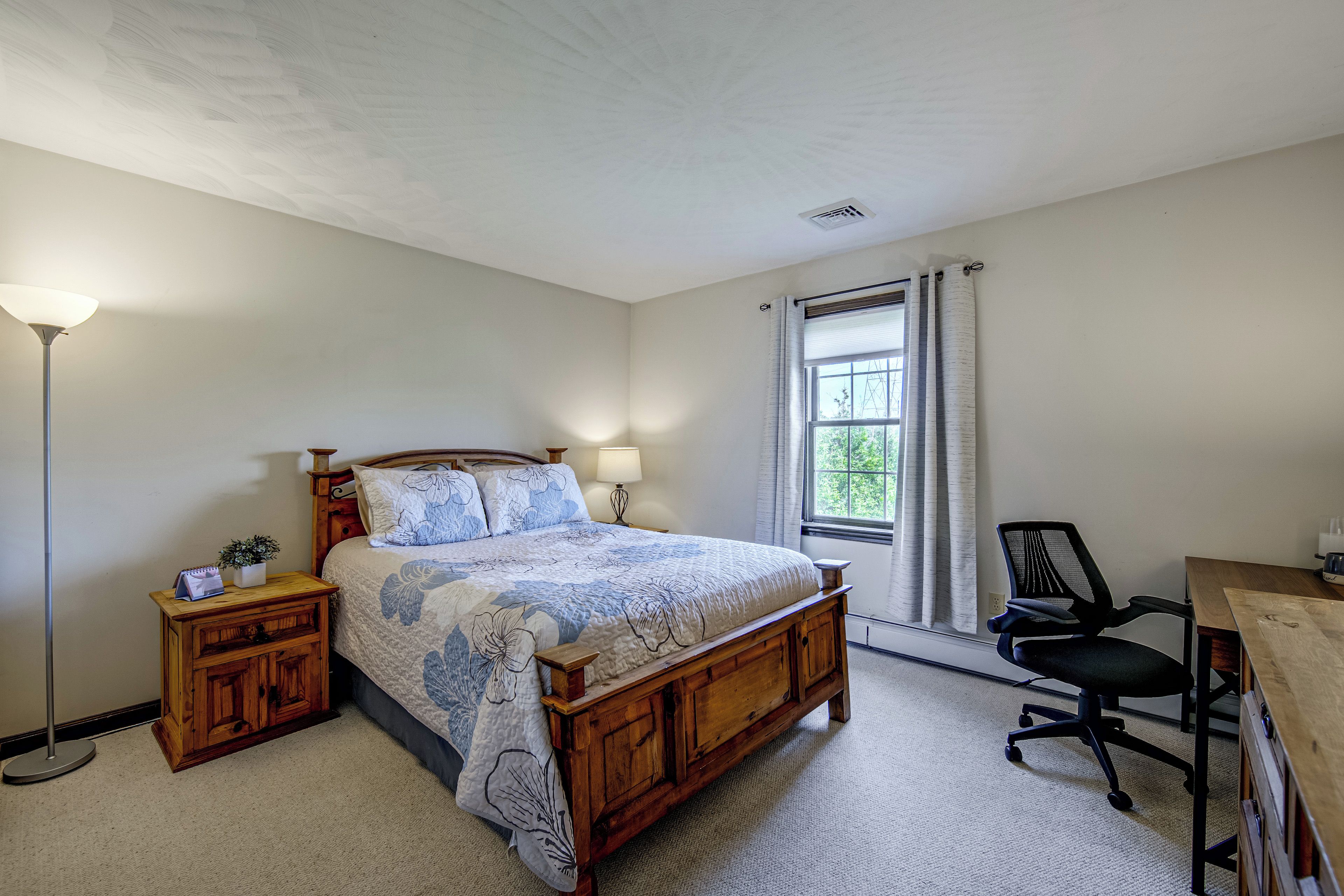 Une chambre à coucher comprenant un lit, des tables de chevet, un bureau et une chaise.