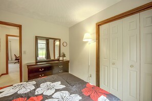 A bedroom with a bed, dresser, mirror, wall clock, and a door. - Charming Lewisburg Home w/ Hot Tub & Games! (Lewisburg)