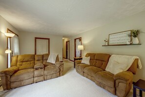 A living room with two sofas, a rug, a lamp, a mirror, and a sign on the wall. - Charming Lewisburg Home w/ Hot Tub & Games! (Lewisburg)