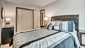Une chambre avec un grand lit, deux tables de chevet, une armoire et un plafond au décor texturé.