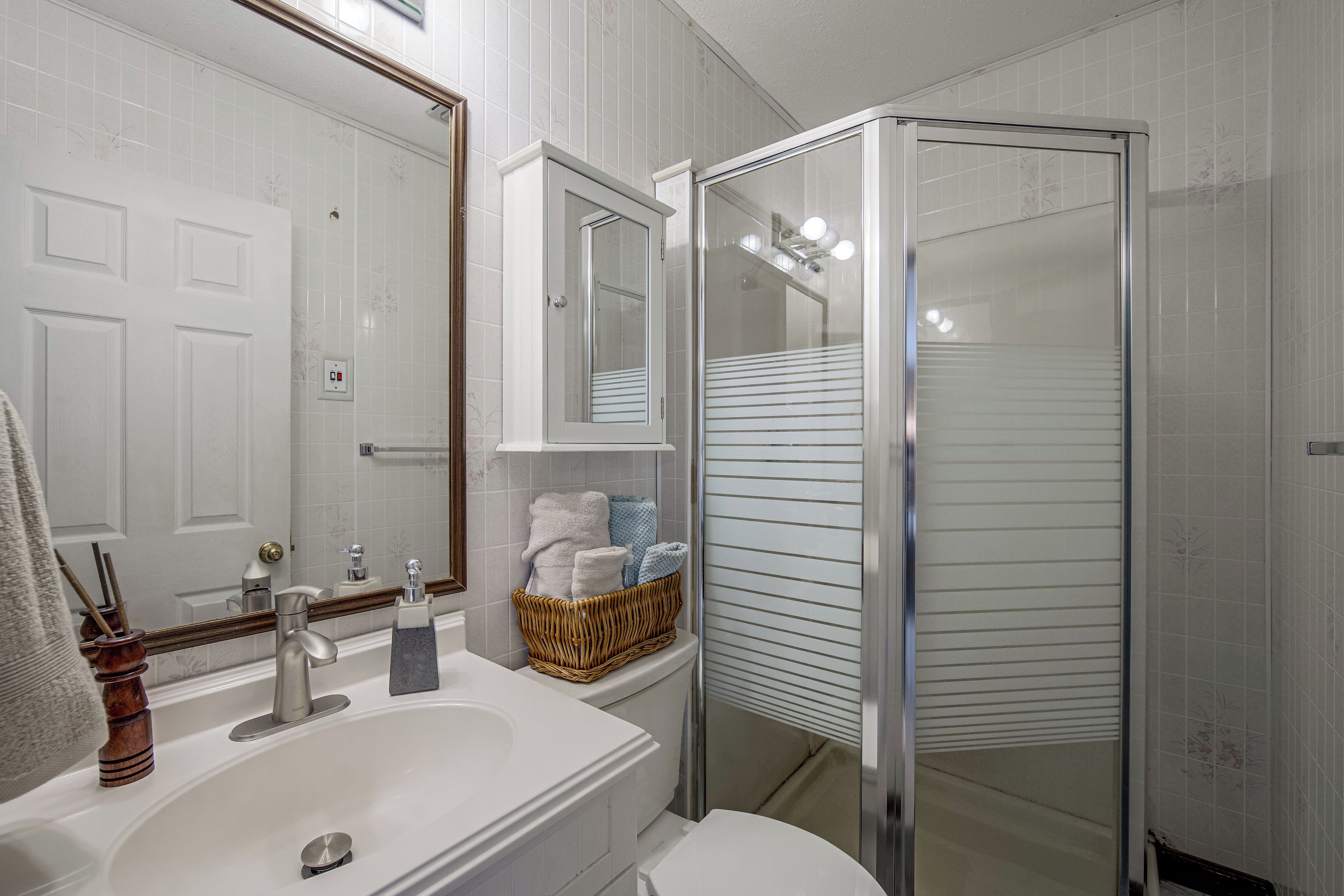 A bathroom with a white sink, mirror, and a glass-enclosed shower.