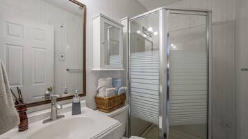 A bathroom with a white sink, mirror, and a glass-enclosed shower.