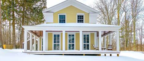 A two-story house with a covered porch and a snow-covered roof.