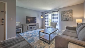 A living room with a flat-screen TV, a coffee table, a sofa, a patterned rug, and a painting on the wall. - Cozy Condo w/ Pool Access in the Heart of Branson! (Branson)