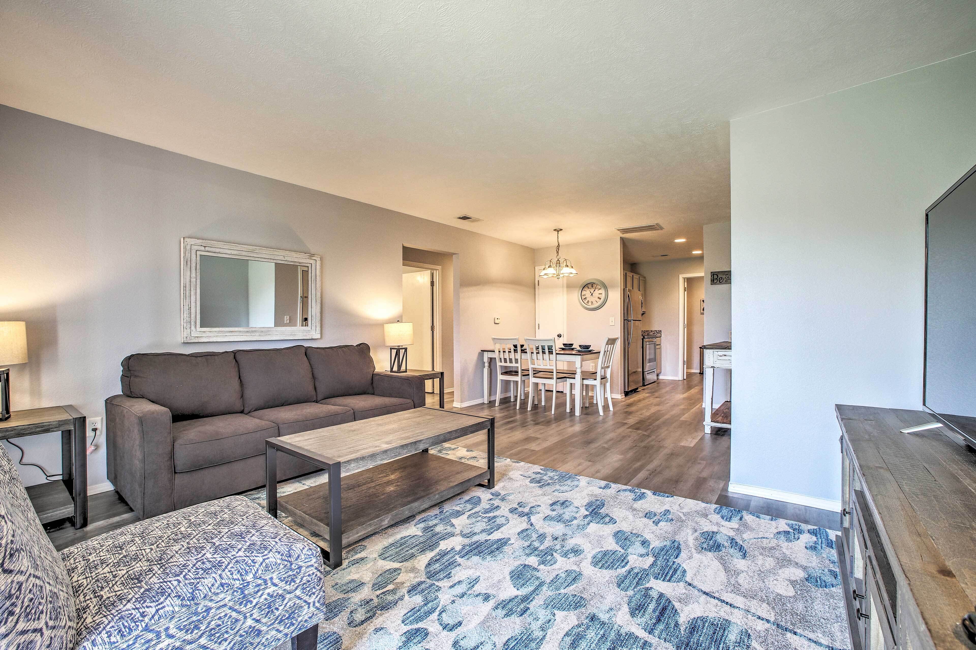 A living room with a sofa, coffee table, patterned rug, and a TV stand.