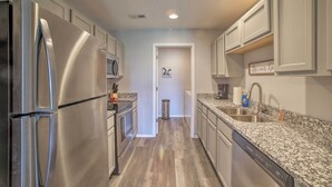 A modern kitchen with stainless steel appliances, granite countertops, and light wood flooring. - Cozy Condo w/ Pool Access in the Heart of Branson! (Branson)