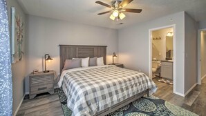 A bedroom with a bed, nightstands, a ceiling fan, and a bathroom visible through an open door. - Cozy Condo w/ Pool Access in the Heart of Branson! (Branson)