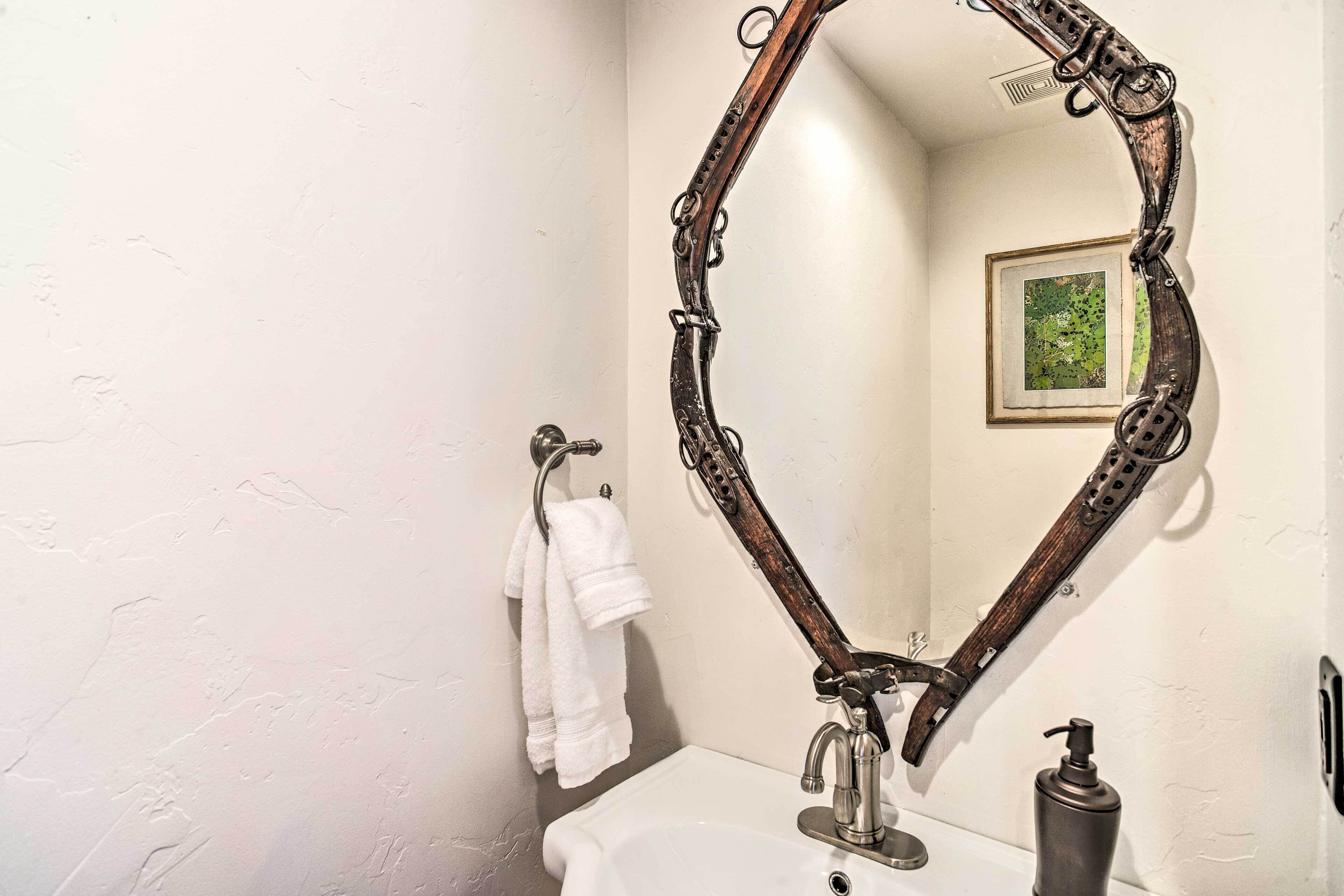 A bathroom with a white sink, a wooden-framed mirror, and a towel rack with a white towel.