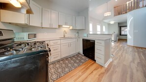 A modern kitchen with white cabinets, a microwave, stove, and dishwasher. - < 3 Mi to Dtwn: Cleveland Apt w/ Deck & Wet Bar (Cleveland)