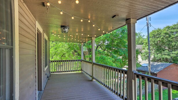 A covered porch with string lights, wooden railings, and a view of a green landscape. - < 3 Mi to Dtwn: Cleveland Apt w/ Deck & Wet Bar (Cleveland)