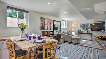 A modern living room with a dining area, a sofa, and a TV.