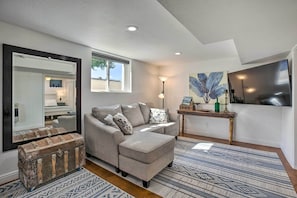 A living room with a sofa, a coffee table, a mirror, a window, and a painting on the wall. - 4 Mi to Coors Field: Charming Apartment w/ Patio (Denver)